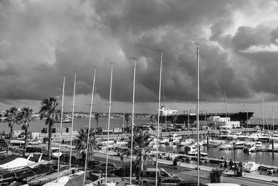 Boats moored at harbor against cloudy sky