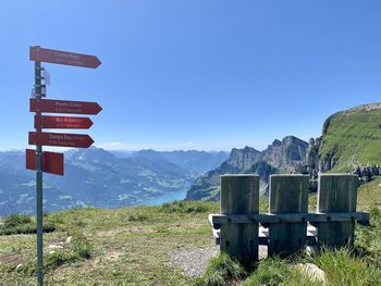 Sign board on mountain against clear blue sky