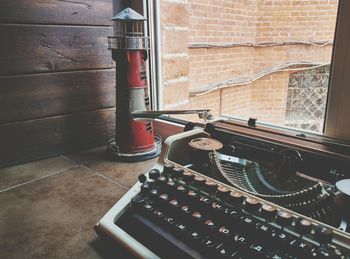 A typewriter and a toy lighthouse stand on the windowsill