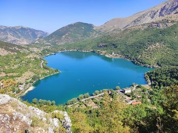 Scenic view of heart shaped lake and mountains against blue sky in scanno