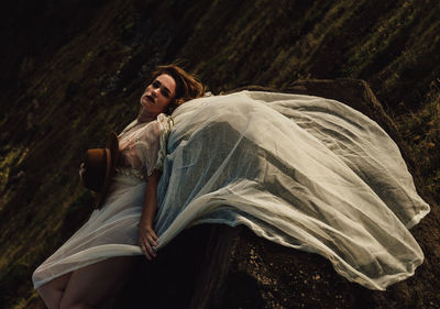 Woman looking away while sitting on land