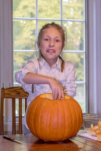 A little girl grimaces at the slimy texture inside her halloween pumpkin.