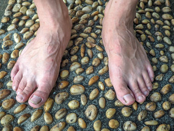 Low section of person legs on pebbles at beach