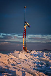 Windmill on snow covered landscape against blue sky