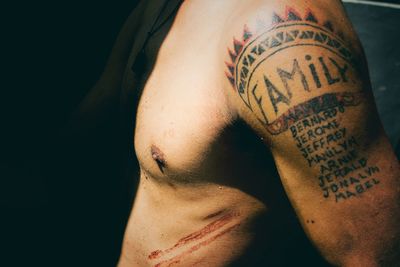 Midsection of shirtless man with tattoo on arm