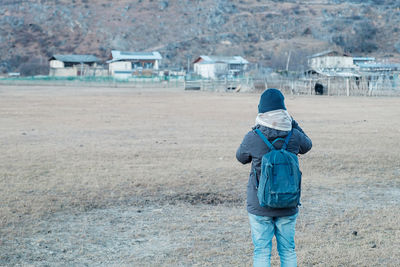 Rear view of man standing on field during winter