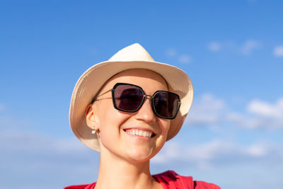 Portrait of smiling woman wearing sunglasses against sky