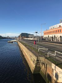 Bridge over river in city against clear sky