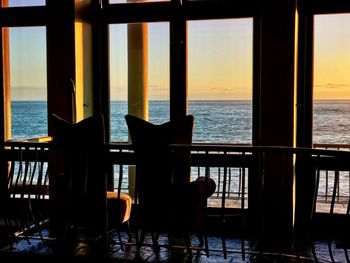 Chairs on beach against sky during sunset