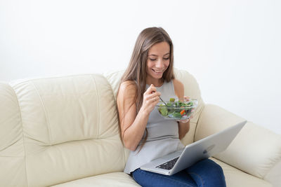 Young woman using phone while sitting on sofa