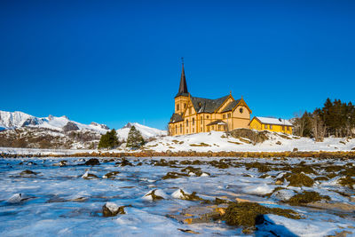 Scenic view of building against clear blue sky during winter