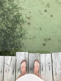 Low section of woman standing on pier over lake