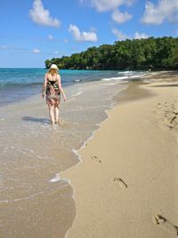 Rear view of woman walking on sea shore at beach