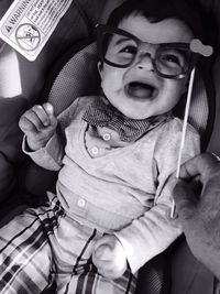 Cute baby boy wearing novelty glasses while lying in stroller