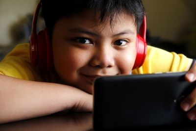 Close-up of boy listening to headphones while using smart phone