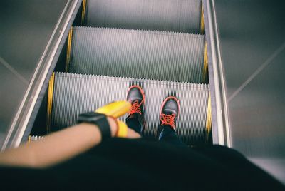 Low section of woman standing on escalator