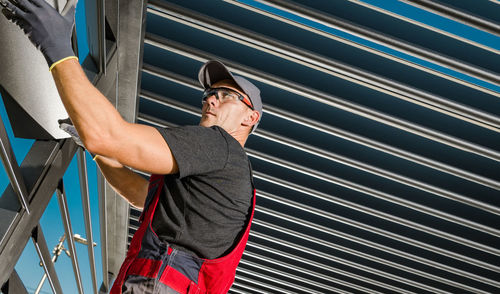 Low angle view of young man standing against wall