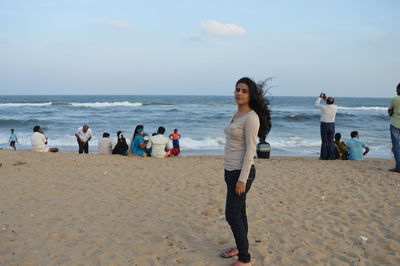 Portrait of woman standing at beach against sky