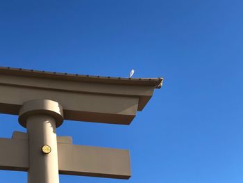 Low angle view of telephone pole against clear blue sky