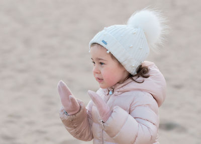 Little girl is playing on an empty beach on a cold day