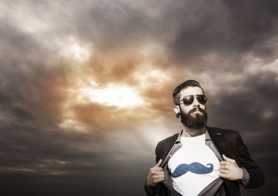 Portrait of young man standing against sky during sunset