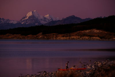 Man walking at lakeshore against mountains