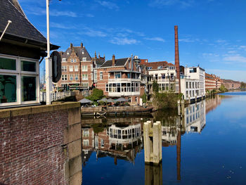 Buildings by river against sky