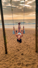 Rear view of woman swinging at beach