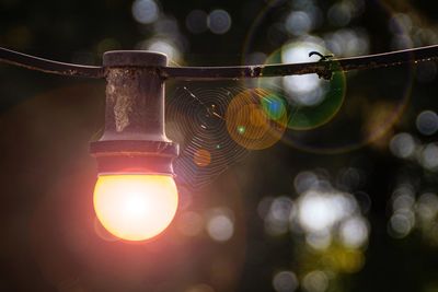 Low angle view of illuminated lighting equipment hanging on rope