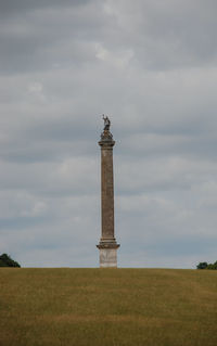 Tower on field against cloudy sky