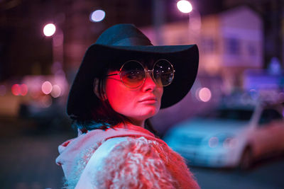 Portrait of woman wearing hat at night