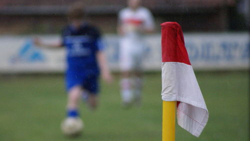 Close-up of flag at soccer field with players in background