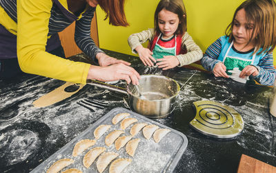 High angle view of mother with daughters preparing food in kitchen