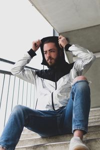 Low angle view of young man smoking cigarette while sitting on steps