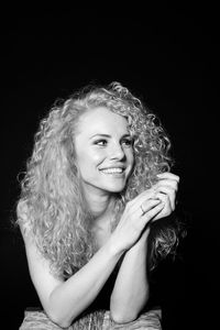 Portrait of smiling young woman against black background