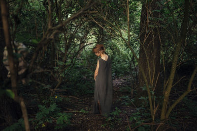 Woman standing back in the forest