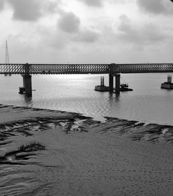 Bridge over calm sea against sky