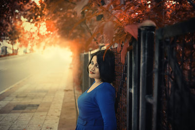 Woman looking away while standing by tree