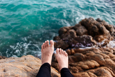 Low section of woman on rock at beach