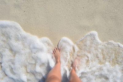 Low section of woman on sand at beach