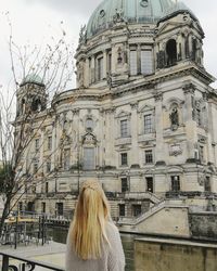 Rear view of woman leaning against building