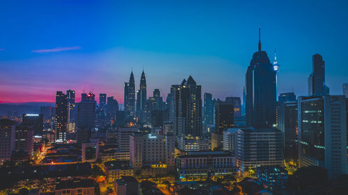 Illuminated modern buildings in city against sky