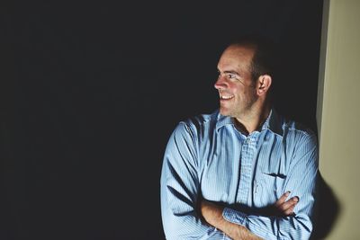 Young man looking away against black background