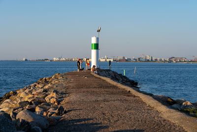 Lighthouse by sea against clear sky