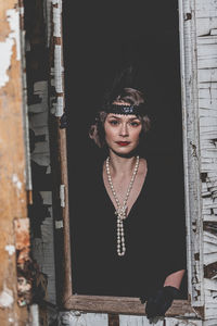 Portrait of young woman standing against door