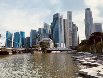 Modern buildings by river against sky in city