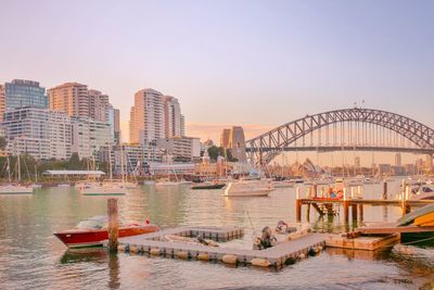 Bridge over river in city during sunset