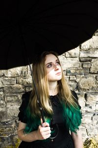 Beautiful young woman standing against wall