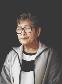 Portrait of smiling senior woman against black background