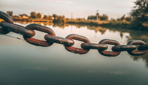 Close-up of chain on riverbank against sky